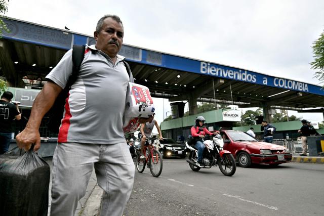 A man carrying toilet paper crosses the Colombia-Venezuela border checkpoint at the Simon Bolivar International Bridge on the outskirts of Cucuta, Colombia on March 12, 2026. The first foreign visit of Venezuela's US-backed interim leader, Delcy Rodriguez, since taking power was abruptly cancelled on March 12, 2026, just hours before she was due to arrive in Colombia, a Colombian foreign ministry source told AFP. (Photo by Luis ACOSTA / AFP)
