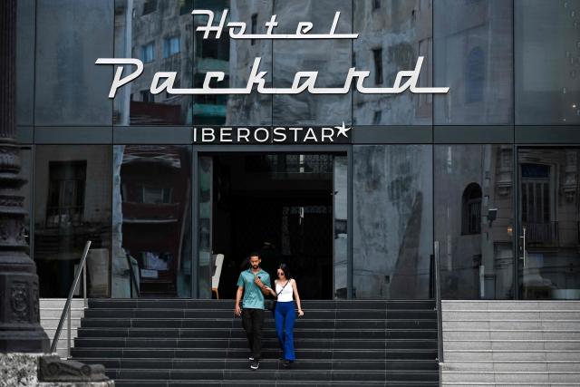 A couple leaves the Iberostar Grand Packard Hotel in Havana on March 12, 2026. (Photo by YAMIL LAGE / AFP)