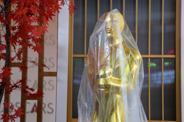 A decorative replica Oscar statue covered in protective plastic sheeting is seen as preparations are made ahead of the 98th Annual Academy Awards outside the Dolby Theatre in Hollywood, California, on March 12, 2026. (Photo by ANGELA WEISS / AFP)