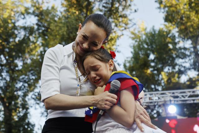 TOPSHOT - Venezuelan opposition leader Maria Corina Machado embraces a girl during an encounter with members of the Venezuelan community in Chile at Almagro Square in Santiago on March 12, 2026. Machado travelled to Chile to attend Chile's President Jose Antonio Kast's inauguration. (Photo by Raul BRAVO / AFP)