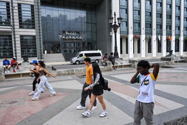 People walk past the Iberostar Grand Packard Hotel in Havana on March 12, 2026. (Photo by YAMIL LAGE / AFP)