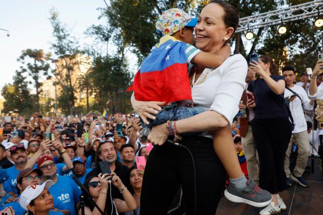 Venezuelan opposition leader Maria Corina Machado embraces a child during an encounter with members of the Venezuelan community in Chile at Almagro Square in Santiago on March 12, 2026. Machado travelled to Chile to attend Chile's President Jose Antonio Kast's inauguration. (Photo by Raul BRAVO / AFP)
