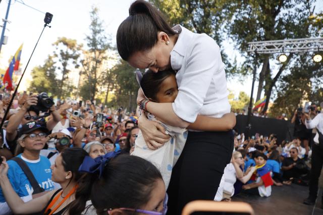 Venezuelan opposition leader Maria Corina Machado embraces a girl during an encounter with members of the Venezuelan community in Chile at Almagro Square in Santiago on March 12, 2026. Machado travelled to Chile to attend Chile's President Jose Antonio Kast's inauguration. (Photo by Raul BRAVO / AFP)