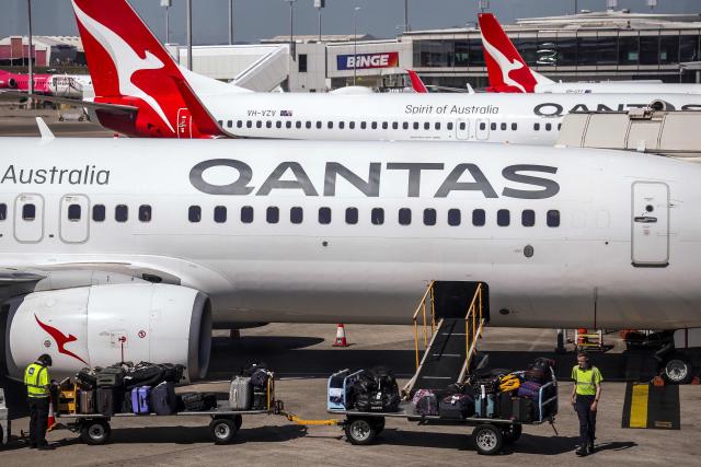 (FILES) This photo taken on August 25, 2025 shows Qantas Airways ground staff loading luggage onto a Boeing 737 aircraft on the tarmac of Brisbane Airport in Queensland. Australia's Qantas Airways said on March 13, 2026, it would pay out 74 million USD to settle a class action alleging it misled customers and failed to provide ticket refunds for flights cancelled during the Covid pandemic. (Photo by DAVID GRAY / AFP)