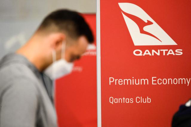 (FILES) Travelers wait in line after verifying their Covid-19 vaccination status as they check-in for a flight to Sydney, Australia on Qantas Airways Ltd. inside the Tom Bradley International Terminal at Los Angeles International Airport (LAX) on November 1, 2021 in Los Angeles, California, as Australia's international border reopens almost 600 days after a pandemic closure began. Australia's Qantas Airways said on March 13, 2026, it would pay out 74 million USD to settle a class action alleging it misled customers and failed to provide ticket refunds for flights cancelled during the Covid pandemic. (Photo by Patrick T. FALLON / AFP)