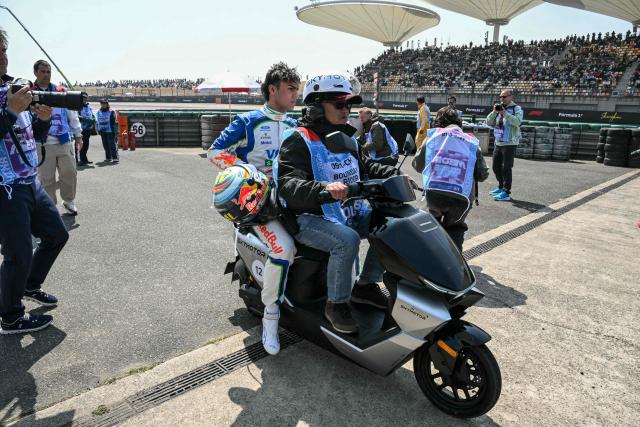 Racing Bulls' British driver Arvid Lindblad (centre L) is transported back to the pits on a scooter during a practice session ahead of the Formula One Chinese Grand Prix at the Shanghai International Circuit in Shanghai on March 13, 2026. (Photo by GREG BAKER / AFP)