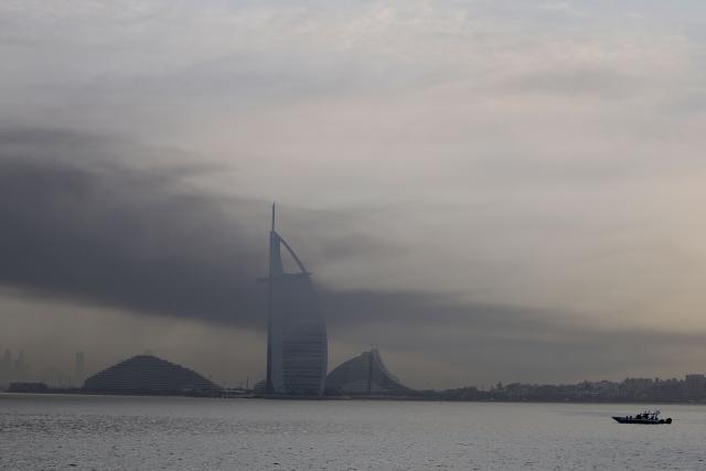 Smoke is seen above Dubai on March 13, 2026. Explosions rattled buildings in Dubai and a large cloud of smoke hung over a central area of the Middle East financial hub on March 13, AFP correspondents said. (Photo by AFP) / 