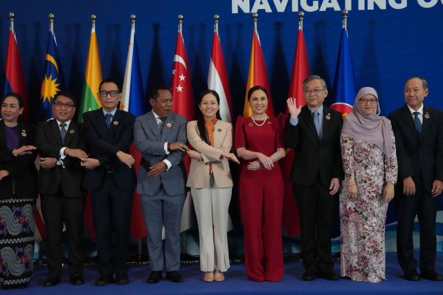 (L-R) Myanmar Union Minister Wah Wah Maung, Philippines Undersecretary Allan Gepty, Thailand Deputy Permanent Secretary Ekachat Seetavorarat, Timor Leste Vice Minister of Commerce Augusto Júnior Trindade, Vietnam deputy director of the department on multilateral trade policy under Ministry of Industry and Trade Nguyen Viet Chi, Philippines Secretary Maria Cristina Aldeguer Roque, Singapore Deputy Prime Minister Kim Yong Gan, Brunei Finance Minister and Economy Hajah May Fa'ezah, Cambodia Secretary of State Pich Rithy, Indonesia Vice Minister of Trade Dyah Roro Esti Widya Putri, Lao Vice Minister Manothong Vongsay and ASEAN Secretary General Kim Hourn Kao link arms during a group photo at the 32nd ASEAN Economic Ministers Retreat and Related Meetings in Manila on March 13, 2026. (Photo by Aaron Favila / POOL / AFP)