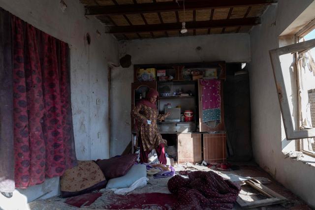 An Afghan woman inspects her damaged house at the site of an overnight Pakistan airstrike, at a residential area in Pol-e-Charkhi on the outskirts of Kabul on March 13, 2026. Afghan authorities said on March 13 that Pakistan had carried out new strikes on Kabul and border provinces, killing four people in the capital. (Photo by Wakil KOHSAR / AFP)