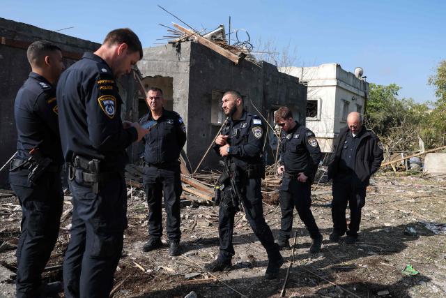Israeli policemen inspect the site of a rocket strike in Zarzir, northern Israel, on March 13, 2026. New waves of attacks struck Iran and Gulf nations on March 13 after Tehran renewed its threats on oil facilities, while France announced its first soldier killed during the Mideast war. The latest strikes on Iran hit over 200 targets in the past day, Israel's military said well into the second week of the US-Israeli campaign that has grown into a deadly regional fight causing economic chaos. (Photo by Odd ANDERSEN / AFP) / 