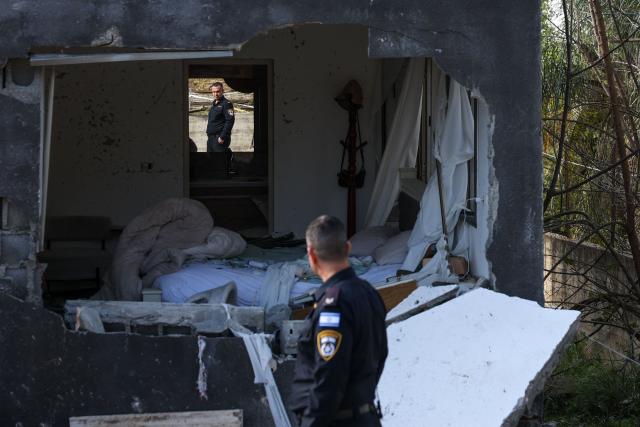 TOPSHOT - An Israeli policeman is reflected in the mirror of a damaged house as he inspects the site of a rocket strike in Zarzir, northern Israel, on March 13, 2026. New waves of attacks struck Iran and Gulf nations on March 13 after Tehran renewed its threats on oil facilities, while France announced its first soldier killed during the Mideast war. The latest strikes on Iran hit over 200 targets in the past day, Israel's military said well into the second week of the US-Israeli campaign that has grown into a deadly regional fight causing economic chaos. (Photo by Odd ANDERSEN / AFP) / 