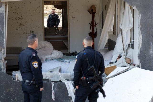 Israeli policemen inspect the site of a rocket strike in Zarzir, northern Israel, on March 13, 2026. New waves of attacks struck Iran and Gulf nations on March 13 after Tehran renewed its threats on oil facilities, while France announced its first soldier killed during the Mideast war. The latest strikes on Iran hit over 200 targets in the past day, Israel's military said well into the second week of the US-Israeli campaign that has grown into a deadly regional fight causing economic chaos. (Photo by Odd ANDERSEN / AFP) / 