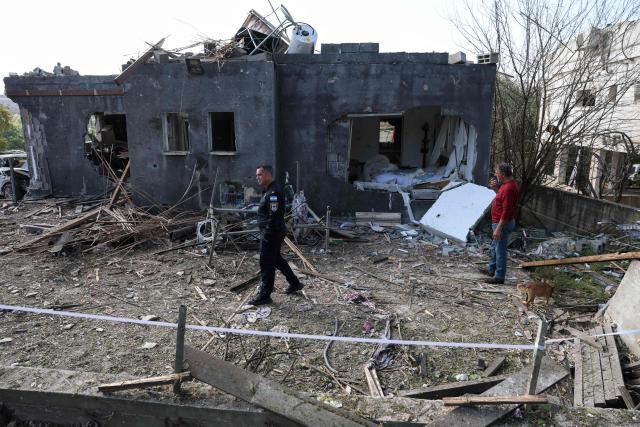 An Israeli policeman inspects the site of a rocket strike in Zarzir, northern Israel, on March 13, 2026. New waves of attacks struck Iran and Gulf nations on March 13 after Tehran renewed its threats on oil facilities, while France announced its first soldier killed during the Mideast war. The latest strikes on Iran hit over 200 targets in the past day, Israel's military said well into the second week of the US-Israeli campaign that has grown into a deadly regional fight causing economic chaos. (Photo by Odd ANDERSEN / AFP) / 