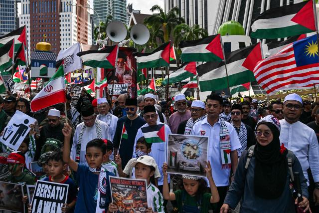 People hold placards and Palestinian flags during a demonstration to mark al-Quds (Jerusalem) Day, after Friday prayers in Kuala Lumpur on March 13, 2026. (Photo by Mohd Rasfan / AFP)