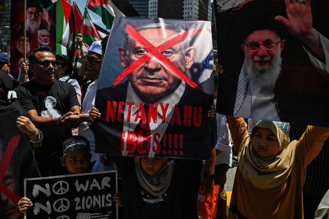 Children hold placards showing Israel's Prime Minister Benjamin Netanyahu (C) and Iran's slain supreme leader Ayatollah Ali Khamenei (R) during a demonstration to mark al-Quds (Jerusalem) Day, after Friday prayers in Kuala Lumpur on March 13, 2026. (Photo by Mohd Rasfan / AFP)