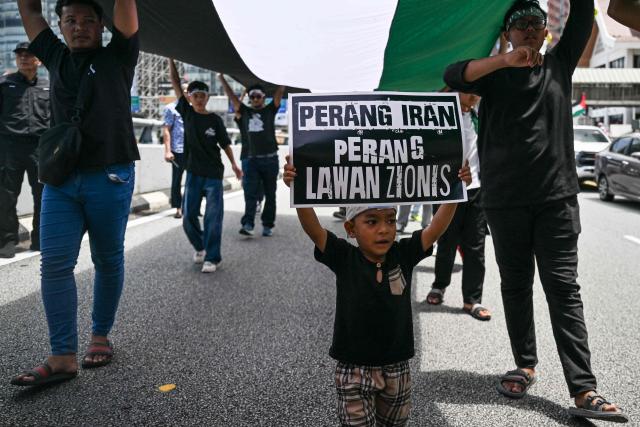 A boy holds a placard reading “Iran war with Zionist” during a demonstration to mark al-Quds (Jerusalem) Day, after Friday prayers in Kuala Lumpur on March 13, 2026. (Photo by Mohd Rasfan / AFP)