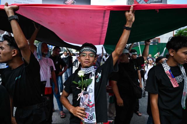 A protestor holds a flower with a portrait of Iran's slain supreme leader Ayatollah Ali Khamenei during a demonstration to mark al-Quds (Jerusalem) Day, after Friday prayers in Kuala Lumpur on March 13, 2026. (Photo by Mohd Rasfan / AFP)