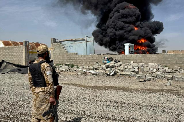 A Taliban security personnel stands as smoke rises from the site after overnight Pakistani airstrikes hit oil depots for commercial airlines, near the Kandahar airport in the Daman district of Kandahar province on March 13, 2026. Afghan authorities said on March 13 that Pakistan attacks on Kabul and border provinces killed four people in the capital and two in the east, the latest deadly clashes in the long-running conflict. (Photo by AFP)