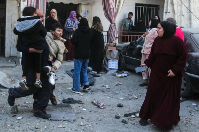 A man carries two children in his arms as he flees the site of an Israeli airstrike that targeted a neighborhood in the town of Mieh Mieh, some five kilometers east of the southern Lebanese city of Sidon on March 13, 2026. Israel continued striking Beirut early March 13, as it threatened to expand operations and seize territory in Lebanon if the militant group Hezbollah did not stop its attacks. (Photo by MAHHMOUD ZAYYAT / AFP)