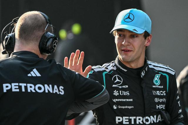 Mercedes' British driver George Russell (R) celebrates with a crew member after getting pole position in the sprint qualifying session ahead of the Formula One Chinese Grand Prix at the Shanghai International Circuit in Shanghai on March 13, 2026. (Photo by Greg Baker / AFP)