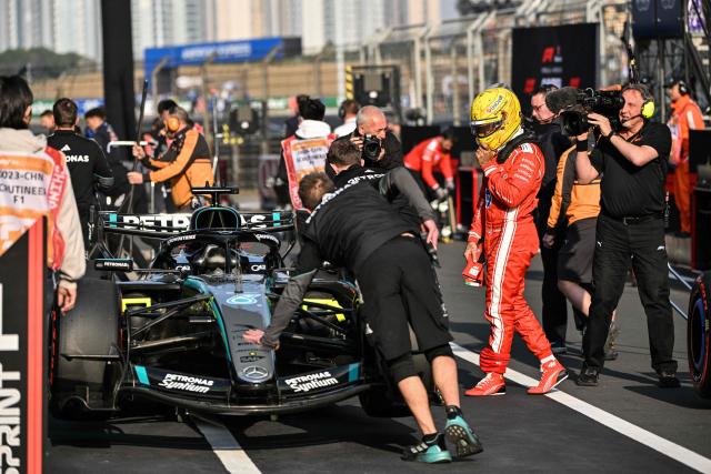 Ferrari's British driver Lewis Hamilton (2R) is seen next to Mercedes' British George Russell car after the sprint qualifying session ahead of the Formula One Chinese Grand Prix at the Shanghai International Circuit in Shanghai on March 13, 2026. (Photo by Hector RETAMAL / AFP)