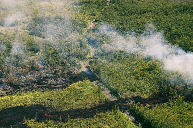 This aerial photograph shows a lava flow making its way through a forested area crossing the RN2 road near Sainte-Rose close to the Piton de la Fournaise volcano in the southeast of the French overseas island of Reunion on March 13, 2026. Two lava flows spewed out by Piton de la Fournaise, a volcano that has been erupting for a month on Rйunion Island, have cut the national road linking the south to the east of the island—something that has not happened in nearly 20 years, the prefecture said on Friday. (Photo by Richard BOUHET / AFP)