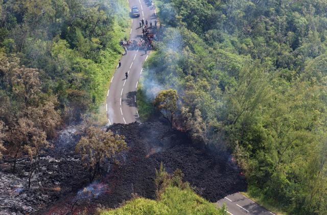 This aerial photograph shows a lava flow making its way through a forested area crossing the RN2 road near Sainte-Rose close to the Piton de la Fournaise volcano in the southeast of the French overseas island of Reunion on March 13, 2026. Two lava flows spewed out by Piton de la Fournaise, a volcano that has been erupting for a month on Rйunion Island, have cut the national road linking the south to the east of the island—something that has not happened in nearly 20 years, the prefecture said on Friday. (Photo by Richard BOUHET / AFP)