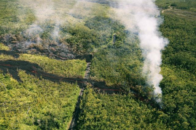 This aerial photograph shows a lava flow making its way through a forested area crossing the RN2 road near Sainte-Rose close to the Piton de la Fournaise volcano in the southeast of the French overseas island of Reunion on March 13, 2026. Two lava flows spewed out by Piton de la Fournaise, a volcano that has been erupting for a month on Rйunion Island, have cut the national road linking the south to the east of the island—something that has not happened in nearly 20 years, the prefecture said on Friday. (Photo by Richard BOUHET / AFP)