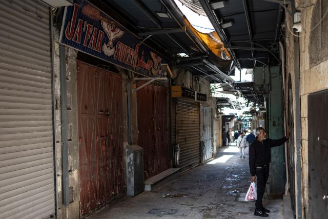 A man knocks at a closed shop in the Old City in Jerusalem on March 13, 2026. New waves of attacks struck Iran and Gulf nations on March 13 after Tehran renewed its threats on oil facilities, while France announced its first soldier killed during the Mideast war. The latest strikes on Iran hit over 200 targets in the past day, Israel's military said well into the second week of the US-Israeli campaign that has grown into a deadly regional fight causing economic chaos. (Photo by OLYMPIA DE MAISMONT / AFP) / 