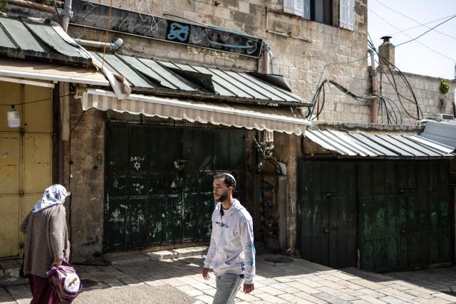 Pedestrians walk past closed shops in the Old City of Jerusalem on March 13, 2026. New waves of attacks struck Iran and Gulf nations on March 13 after Tehran renewed its threats on oil facilities, while France announced its first soldier killed during the Mideast war. The latest strikes on Iran hit over 200 targets in the past day, Israel's military said well into the second week of the US-Israeli campaign that has grown into a deadly regional fight causing economic chaos. (Photo by OLYMPIA DE MAISMONT / AFP) / 