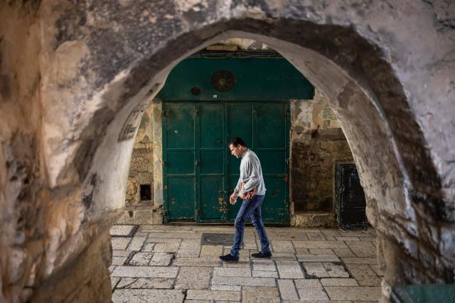 A man walks past a closed shop in the Old City of Jerusalem on March 13, 2026. New waves of attacks struck Iran and Gulf nations on March 13 after Tehran renewed its threats on oil facilities, while France announced its first soldier killed during the Mideast war. The latest strikes on Iran hit over 200 targets in the past day, Israel's military said well into the second week of the US-Israeli campaign that has grown into a deadly regional fight causing economic chaos. (Photo by OLYMPIA DE MAISMONT / AFP) / 