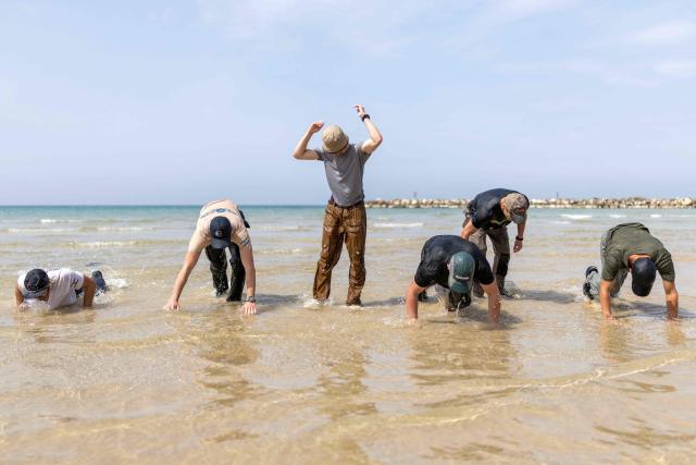 Young Israeli men perform a pre-military training on the beach in Tel Aviv on March 13, 2026. Fresh strikes rocked Iran and several Gulf countries, as Israel and the Islamic republic unleashed a new wave of attacks in a war that has ignited the Middle East and threatens to torpedo the world economy. (Photo by Ilia YEFIMOVICH / AFP) / 