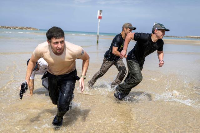 Young Israeli men perform a pre-military training on the beach in Tel Aviv on March 13, 2026. Fresh strikes rocked Iran and several Gulf countries, as Israel and the Islamic republic unleashed a new wave of attacks in a war that has ignited the Middle East and threatens to torpedo the world economy. (Photo by Ilia YEFIMOVICH / AFP) / 