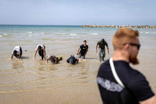 Young Israeli men perform a pre-military training on the beach in Tel Aviv on March 13, 2026. Fresh strikes rocked Iran and several Gulf countries, as Israel and the Islamic republic unleashed a new wave of attacks in a war that has ignited the Middle East and threatens to torpedo the world economy. (Photo by Ilia YEFIMOVICH / AFP) / 