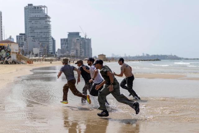 Young Israeli men perform a pre-military training on the beach in Tel Aviv on March 13, 2026. Fresh strikes rocked Iran and several Gulf countries, as Israel and the Islamic republic unleashed a new wave of attacks in a war that has ignited the Middle East and threatens to torpedo the world economy. (Photo by Ilia YEFIMOVICH / AFP) / 