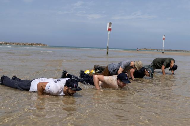 Young Israeli men perform a pre-military training on the beach in Tel Aviv on March 13, 2026. Fresh strikes rocked Iran and several Gulf countries, as Israel and the Islamic republic unleashed a new wave of attacks in a war that has ignited the Middle East and threatens to torpedo the world economy. (Photo by Ilia YEFIMOVICH / AFP) / 