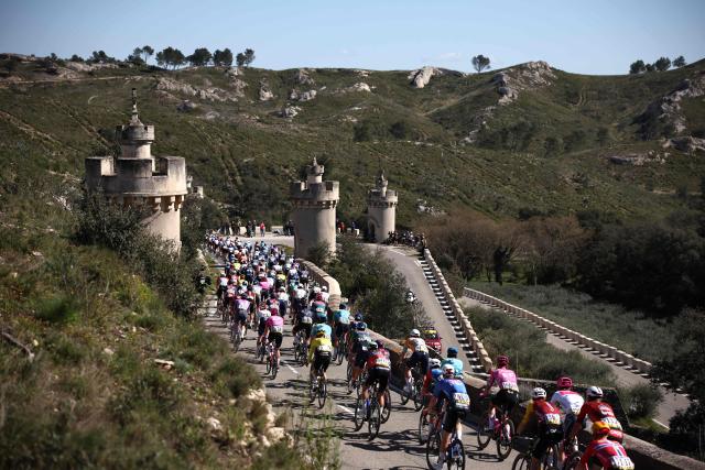 The pack rides past the stations of the Cross, a road leading to the Frigolet Abbey in Tarascon during the 6th stage of the Paris-Nice cycling race, 179.3 km between Barbentane and Apt, on March 13, 2026. (Photo by Anne-Christine POUJOULAT / AFP)