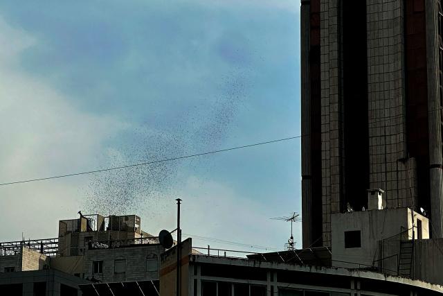 Flyers dropped by Israeli planes are seen scattered across the sky over Beirut on March 13, 2026. Israel's defence minister on March 13, said Lebanon will suffer increasing damage to its infrastructure as Israel targets Hezbollah, after the military destroyed a bridge over the southern Litani river. (Photo by Joseph EID / AFP)
