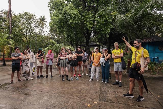 Tourist guide Roderick speaks with a group of tourists during a guided tour through the scenarios of the film "O Agente Secreto" (The Secret Agent) at the city center of Recife, Pernambuco state, Brazil, on February 13, 2026. The northeastern Brazilian city of Recife, where the Oscar-nominated movie "The Secret Agent" is set, is revelling in its moment in the limelight as tourists flock to film locations and a classic local shirt flies off the shelves. (Photo by BRENDA ALCANTARA / AFP)
