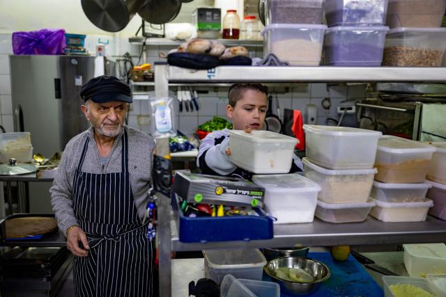 Aaron Yaakobi (L) and his grand son Aaron Alon work in his Persian restaurant Ochlim Bashuk in Jerusalem on March 11, 2026. More than 300,000 Jews of Iranian origin are thought to live in Israel today, the vast majority of whom are those who arrived after 1979 and their descendants. (Photo by Odd ANDERSEN / AFP) / TO GO WITH WAR-IRAN-US-ISRAEL-DIASPORA, FOCUS BY MICHAEL BLUM