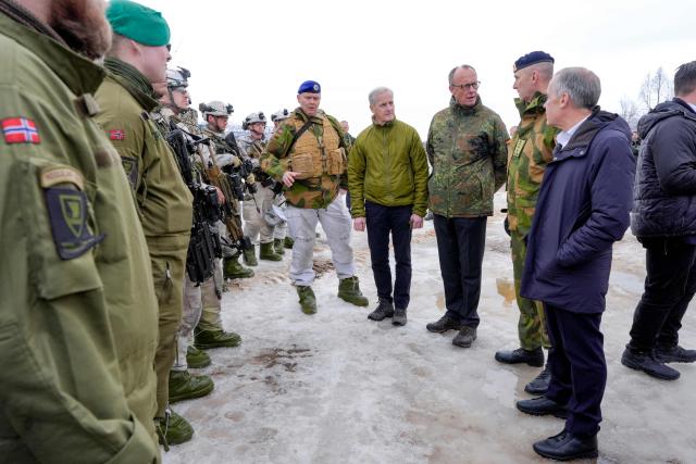 Norway's Prime Minister Jonas Gahr Stoere (2ndL), German Chancellor Friedrich Merz (C) and Canadian Prime Minister Mark Carney (R) talk with soldiers during a visit at the Bardufoss Airbase in Norway on March 13, 2026. Canadian, German and Norwegian leaders are meeting in the Norwegian Arctic on March 13 to discuss the region's fragile security situation, against the backdrop of a large NATO exercise. (Photo by Lise Åserud / NTB / AFP) / Norway OUT