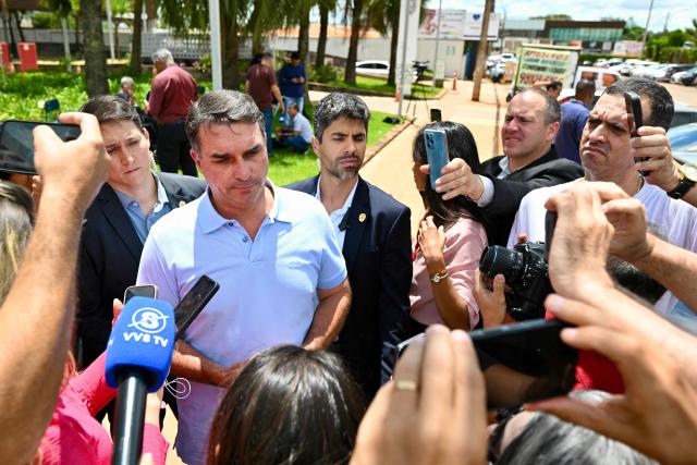 Brazilian Senator Flavio Bolsonaro (2-L), son of former President (2019–2022) Jair Bolsonaro, speaks to the press after visiting his father, who had been admitted to the DF Star Hospital after falling ill in the early hours of the morning at the Papuda prison in Brasilia on March 13, 2026. Former Brazilian president Jair Bolsonaro was taken to hospital onn March 13, 2026 after feeling unwell at the prison where he is serving a sentence for plotting a coup, his son said. (Photo by Evaristo Sa / AFP)