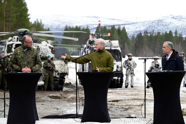 (From L) German Chancellor Friedrich Merz, Norway's Prime Minister Jonas Gahr Stoere and Canadian Prime Minister Mark Carney pose with soldiers in front of a Leopard 2 tank during a visit at the Bardufoss Airbase in Norway on March 13, 2026. Canadian, German and Norwegian leaders are meeting in the Norwegian Arctic on March 13 to discuss the region's fragile security situation, against the backdrop of a large NATO exercise. (Photo by John MACDOUGALL / NTB / AFP)