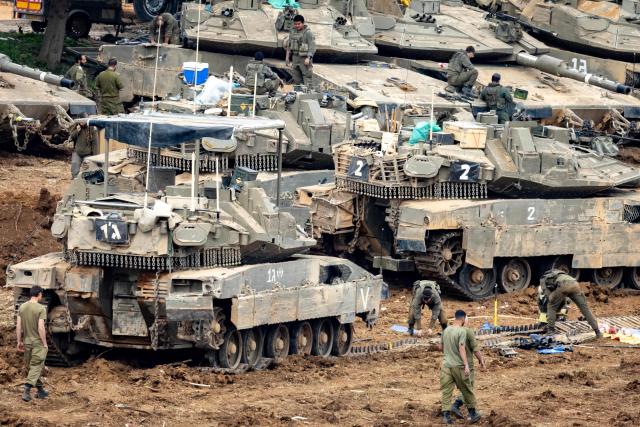 TOPSHOT - Israeli soldiers work on the belts for their tanks at a staging area in the Upper Galilee in northern Israel near the border with Lebanon on March 13, 2026. The Israeli defence minister on March 13, said Lebanon will suffer increasing damage to its infrastructure as Israel targets Hezbollah, after the military destroyed a bridge over the southern Litani river. (Photo by Odd ANDERSEN / AFP) / 