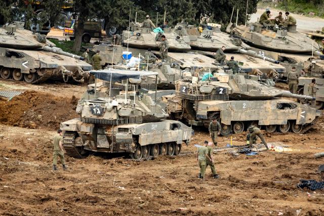 Israeli soldiers work on the belts for their tanks at a staging area in the Upper Galilee in northern Israel near the border with Lebanon on March 13, 2026. Israel's defence minister on March 13, said Lebanon will suffer increasing damage to its infrastructure as Israel targets Hezbollah, after the military destroyed a bridge over the southern Litani river. (Photo by Odd ANDERSEN / AFP) / 