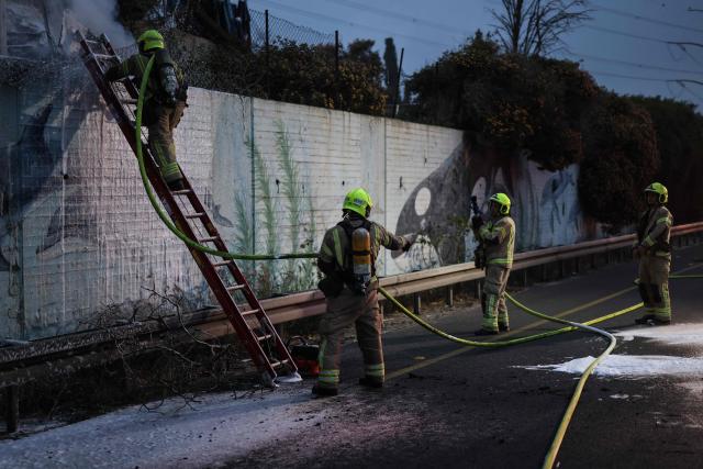Firefighters extinguish a fire at the site of a strike on the outskirts of Tel Aviv on March 13, 2026. Several blasts were heard on March 13, after air raid sirens sounded in Israel's commercial hub Tel Aviv, AFP journalists said, following a warning from the military that missiles had been fired from Iran. (Photo by Ilia YEFIMOVICH / AFP) / 