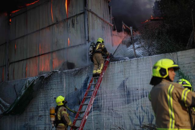 Firefighters extinguish a fire at the site of a strike on the outskirts of Tel Aviv on March 13, 2026. Several blasts were heard on March 13, after air raid sirens sounded in Israel's commercial hub Tel Aviv, AFP journalists said, following a warning from the military that missiles had been fired from Iran. (Photo by Ilia YEFIMOVICH / AFP) / 