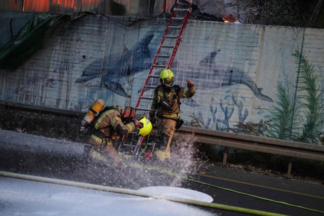 Firefighters extinguish a fire at the site of a strike on the outskirts of Tel Aviv on March 13, 2026. Several blasts were heard on March 13, after air raid sirens sounded in Israel's commercial hub Tel Aviv, AFP journalists said, following a warning from the military that missiles had been fired from Iran. (Photo by Ilia YEFIMOVICH / AFP) / 