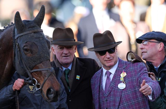 Gaelic Warrior owner Rich Ricci celebrates with trainer Willie Mullins after jockey Paul Townend rode to win the Gold Cup chase horse race on the fourth day of the Cheltenham Festival at Cheltenham Racecourse, in Cheltenham, western England on March 13, 2026. (Photo by Adrian Dennis / AFP)