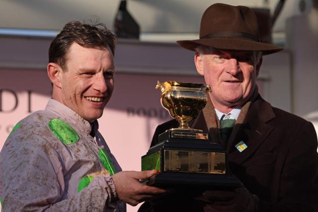 Jockey Paul Townend (L) and trainer Willie Mullins celebrate with the Gold Cup trophy after Gaelic Warrior won the Gold Cup chase horse race on the fourth day of the Cheltenham Festival at Cheltenham Racecourse, in Cheltenham, western England on March 13, 2026. (Photo by Adrian Dennis / AFP)